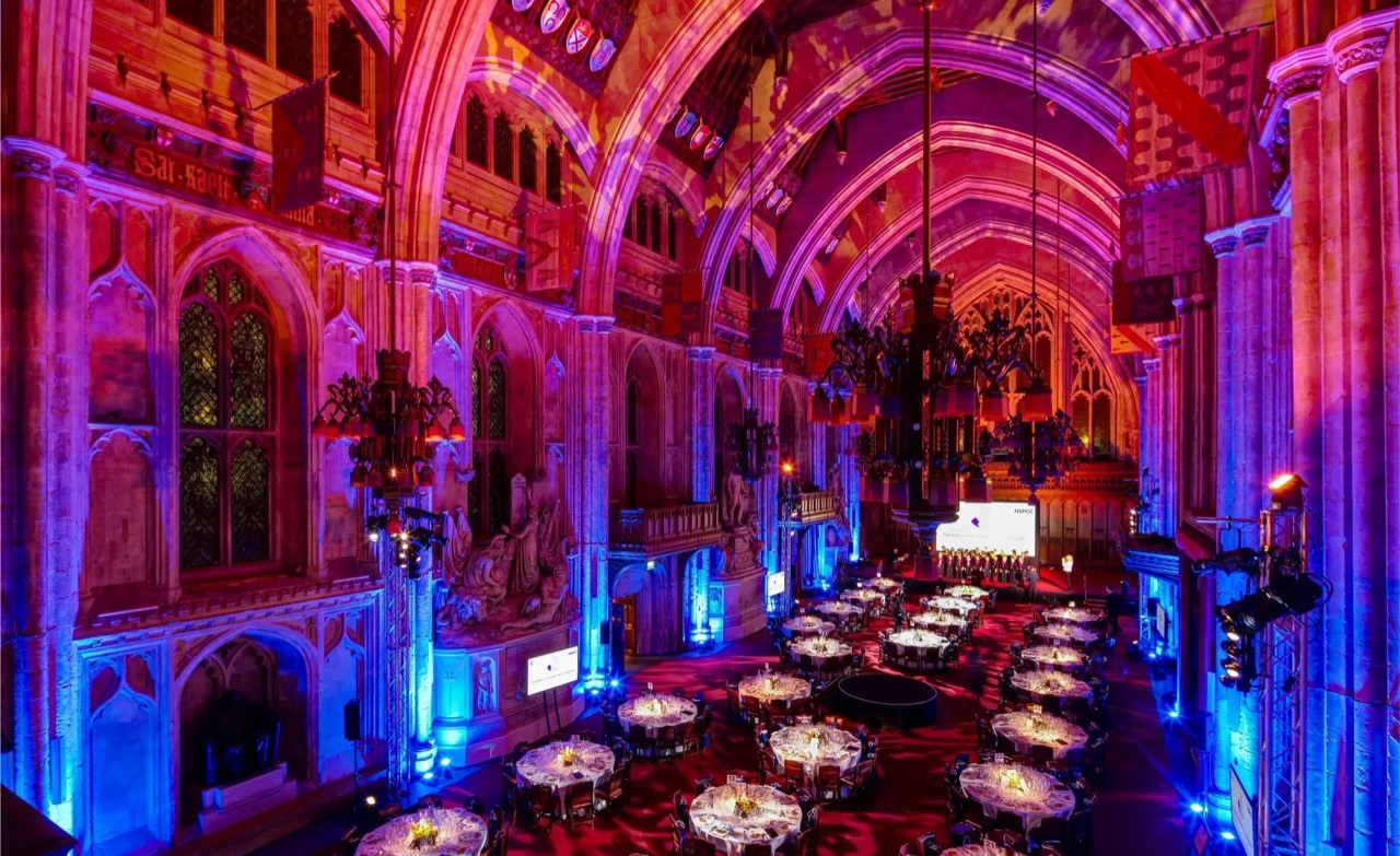 The Great Hall at Guildhall dressed for a gala dinner, with round tables under the vaulted roof lit in blue and red