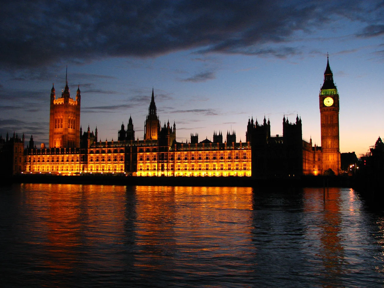 The Palace of Westminster illuminated beside the River Thames at dusk